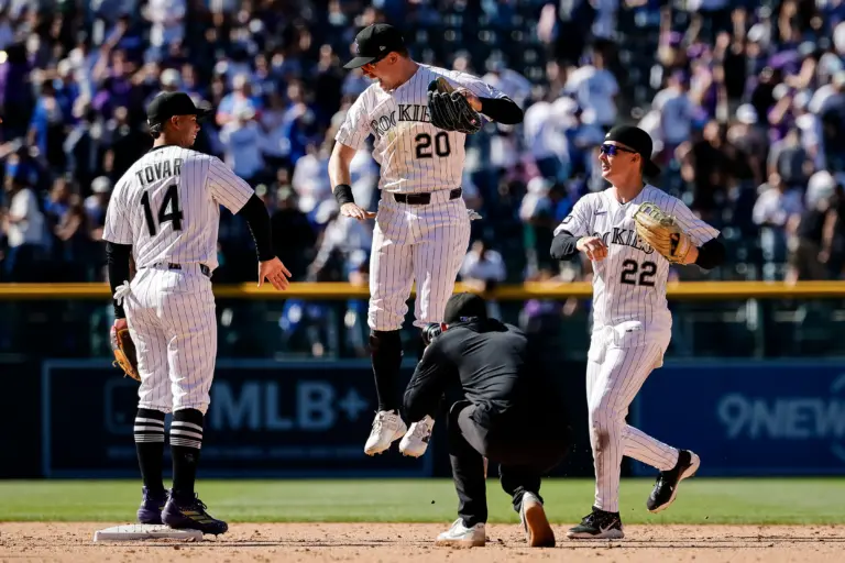 Colorado Rockies players celebrating following a 9-6 win over the Los Angeles Dodgers at Coors Field in Denver, Colorado on Sunday, April 21. Pitcured are shortstop Ezequiel Tovar, outfielder Mickey Moniak, and Troy Johnston jumping in the air to high-five Tovar.