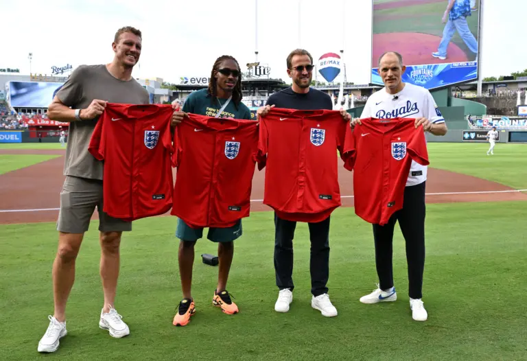 England's Dan Burn, Djed Spence, Harry Kane and manager Thomas Tuchel hold up shirts at the St. Louis Cardinals vs Kansas City Royals MLB game in Kansas City.
