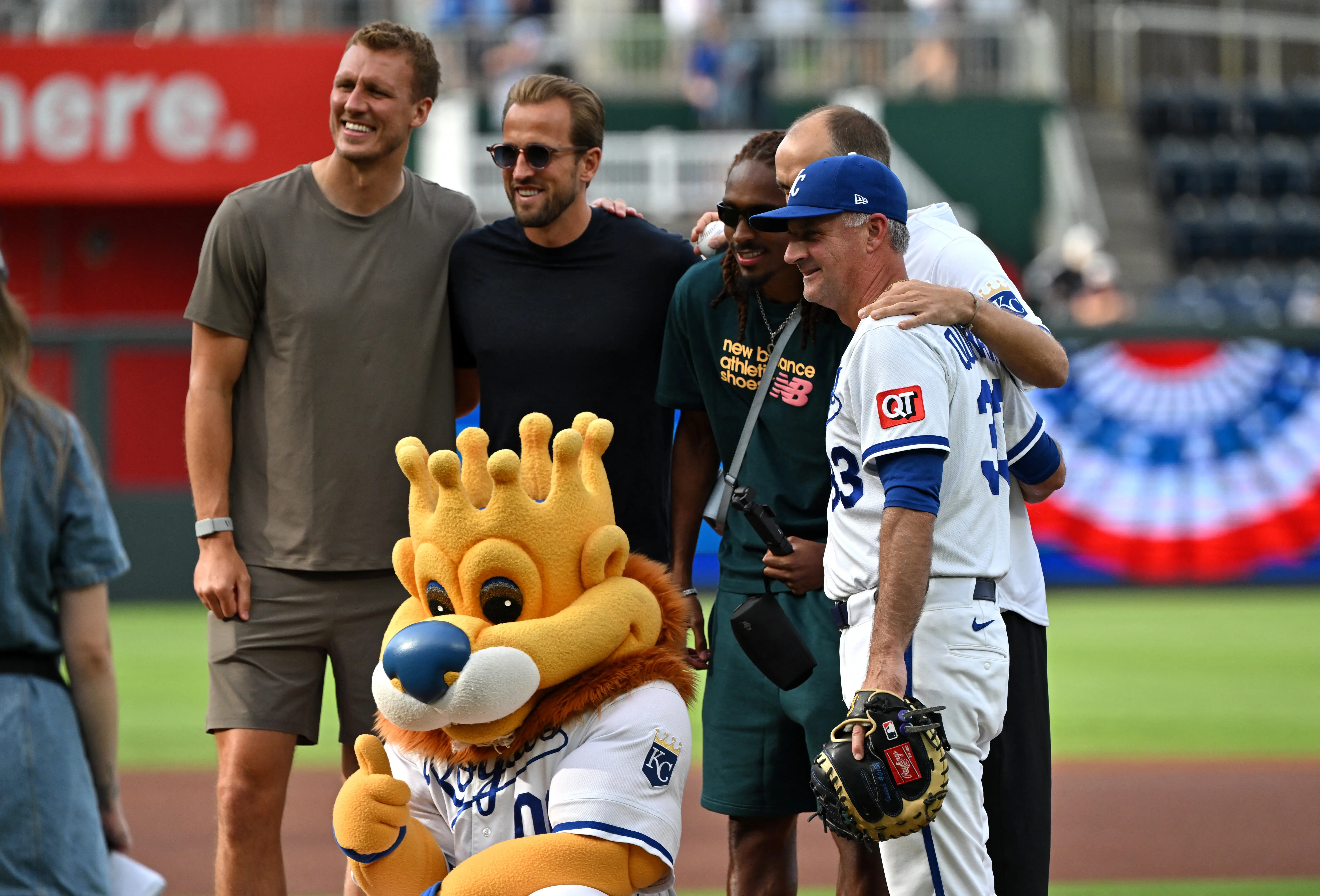 England's Dan Burn, Djed Spence, Harry Kane, manager Thomas Tuchel, Kansas City Royals mascot Sluggerrr and Kansas City Royals manager Matt Quatraro pose for a picture at the St. Louis Cardinals vs Kansas City Royals MLB game in Kansas City. 