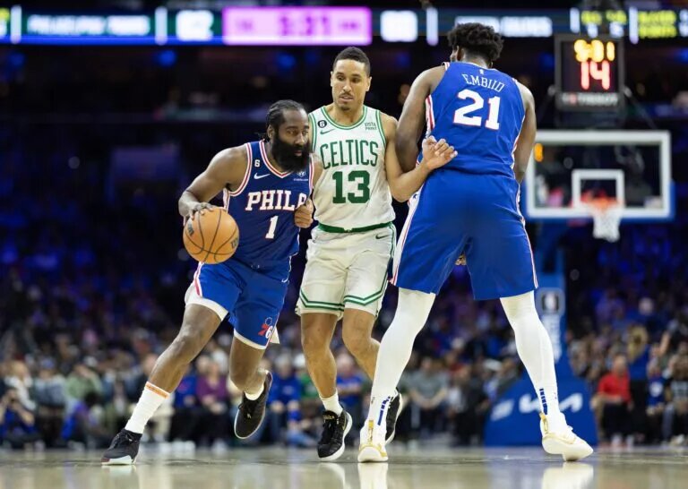 Apr 4, 2023; Philadelphia, Pennsylvania, USA; Philadelphia 76ers guard James Harden (1) drives past Boston Celtics guard Malcolm Brogdon (13) in front of center Joel Embiid (21) during the third quarter at Wells Fargo Center. Mandatory Credit: Bill Streicher-USA TODAY Sports