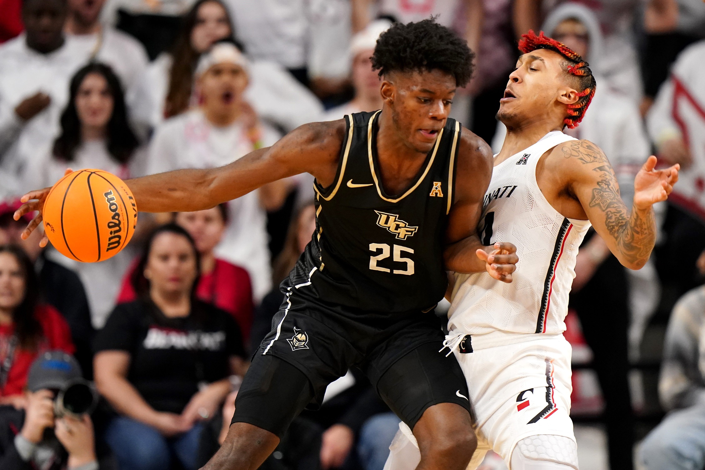 Cincinnati Bearcats guard Jeremiah Davenport (24) draws a charge foul against UCF Knights forward Taylor Hendricks (25) in the first half of a college basketball game between the UCF Knights and the Cincinnati Bearcats, Saturday, Feb. 4, 2023, at Fifth Third Arena in Cincinnati. Ucf Knights At Cincinnati Bearcats Feb 4 0123
