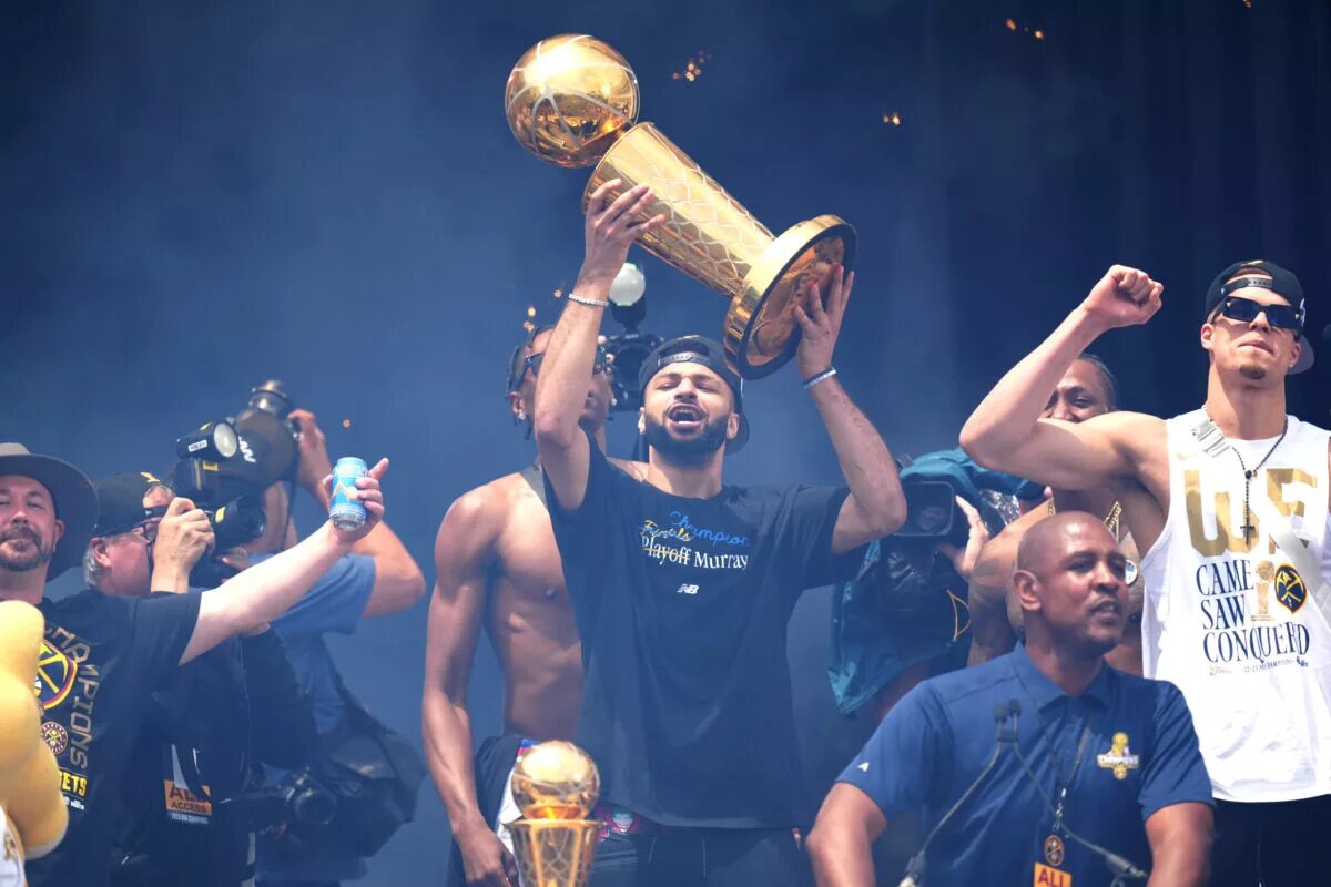 Denver Nuggets point guard Jamal Murray holding the Larry O'Brien trophy over his head at the Nuggets Championship parade