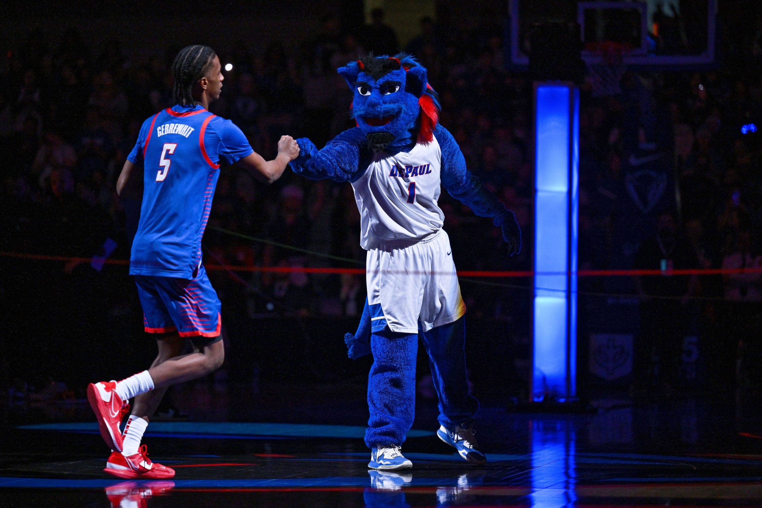 Jan 28, 2023; Chicago, Illinois, USA; The DePaul Blue Demon mascot fist bumps DePaul Blue Demons guard Philmon Gebrewhit (5) as he takes the court before a game against the Marquette Golden Eagles at Wintrust Arena. Mandatory Credit: Jamie Sabau-USA TODAY Sports