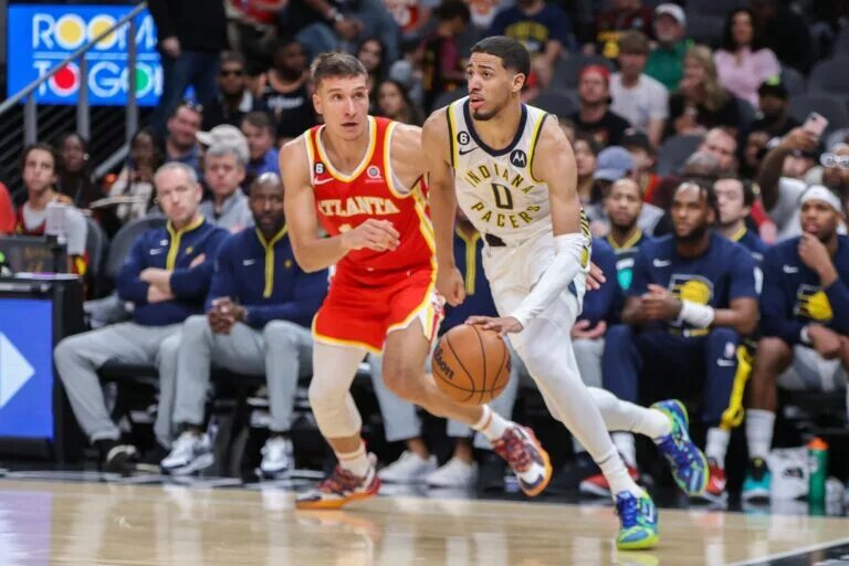 Mar 25, 2023; Atlanta, Georgia, USA; Indiana Pacers guard Tyrese Haliburton (0) drives past Atlanta Hawks guard Bogdan Bogdanovic (13) in the second quarter at State Farm Arena. Mandatory Credit: Brett Davis-USA TODAY Sports