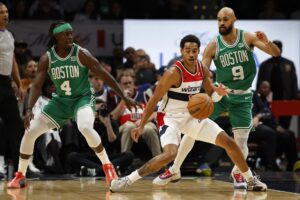 Washington Wizards guard Jordan Poole (13) dribbles the ball as Boston Celtics guard Jrue Holiday (4) and Celtics guard Derrick White (9) defend in the second quarter at Capital One Arena.