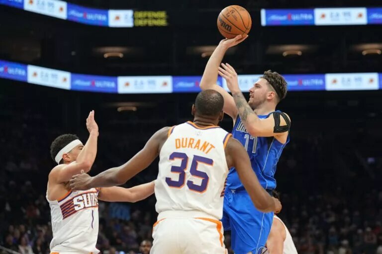 Dec 25, 2023; Phoenix, Arizona, USA; Dallas Mavericks guard Luka Doncic (77) shoots over Phoenix Suns guard Devin Booker (1) and Phoenix Suns forward Kevin Durant (35) during the second half at Footprint Center. Mandatory Credit: Joe Camporeale-USA TODAY Sports