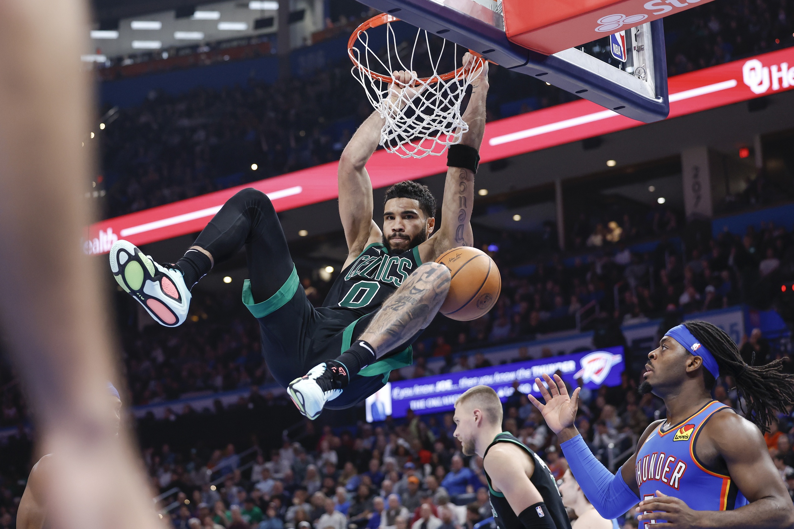 Boston Celtics forward Jayson Tatum (0) hangs on the rim after dunking against the Oklahoma City Thunder during the second half at Paycom Center.