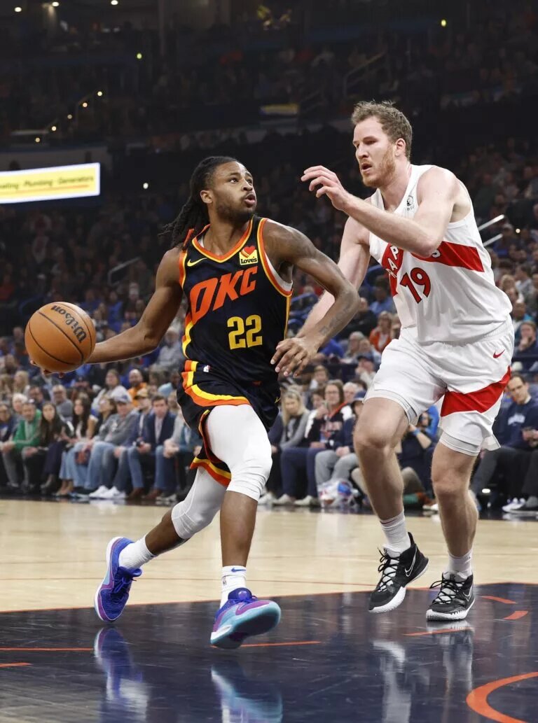 Oklahoma City Thunder guard Cason Wallace (22) drives to the basket beside Toronto Raptors center Jakob Poeltl (19) during the first quarter at Paycom Center.