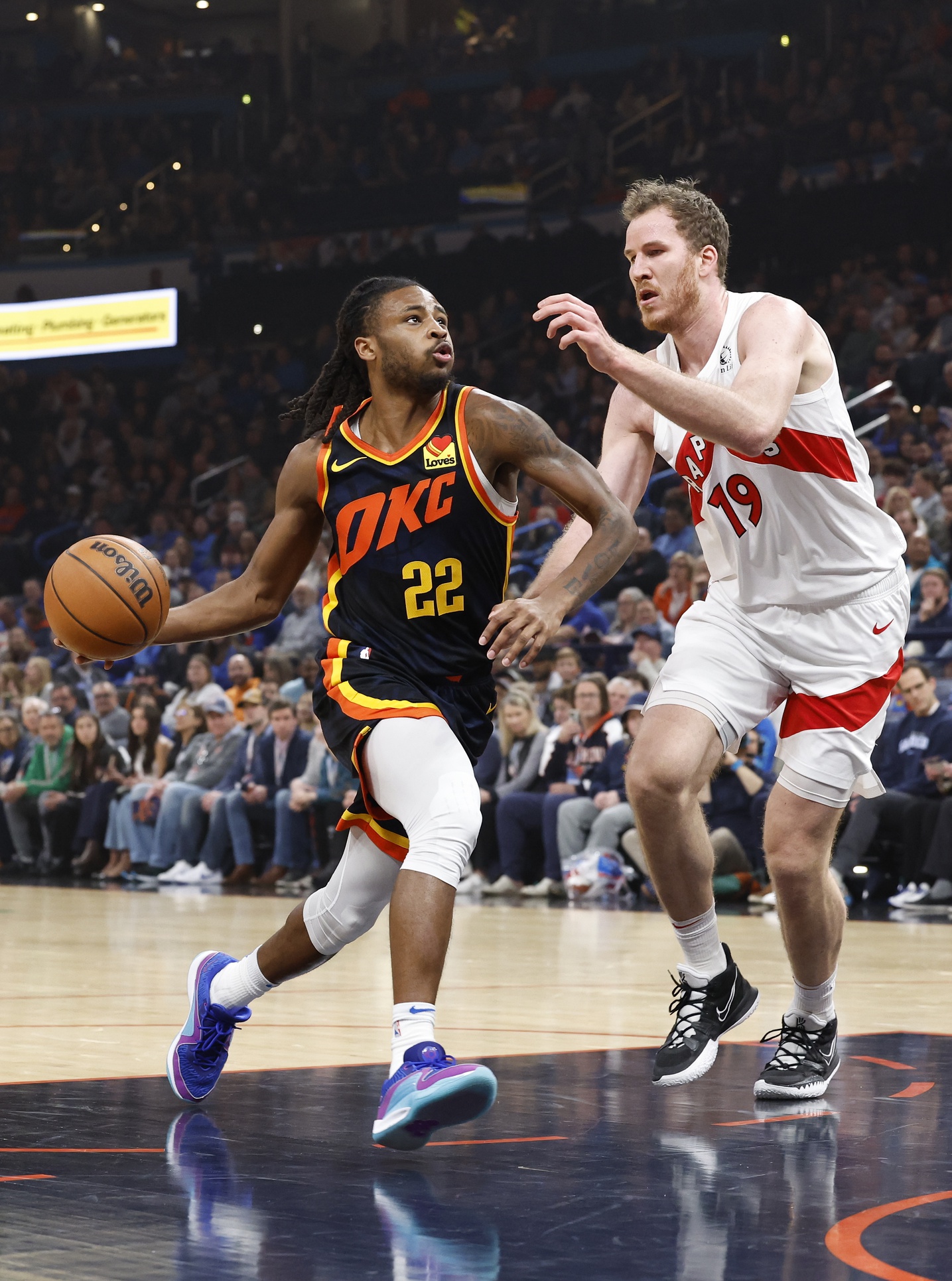 Oklahoma City Thunder guard Cason Wallace (22) drives to the basket beside Toronto Raptors center Jakob Poeltl (19) during the first quarter at Paycom Center.
