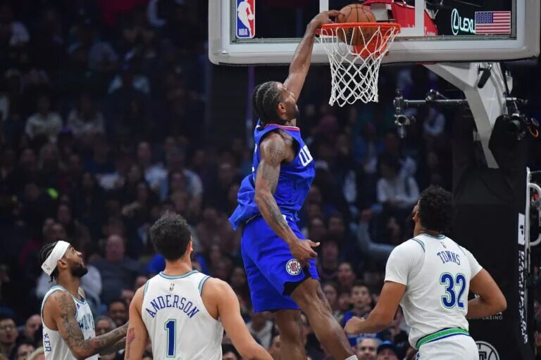 Los Angeles Clippers forward Kawhi Leonard (2) dunks for the basket against Minnesota Timberwolves center Karl-Anthony Towns (32) and forward Kyle Anderson (1) during the first half at Crypto.com Arena.