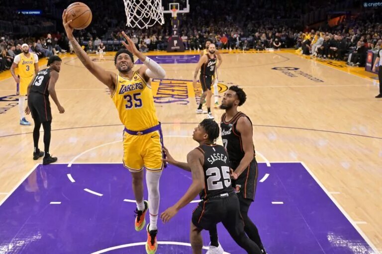 Feb 13, 2024; Los Angeles, California, USA; Los Angeles Lakers forward Christian Wood (35) drives past Detroit Pistons guard Marcus Sasser (25) and guard Troy Brown, Jr. in the first half at Crypto.com Arena. Mandatory Credit: Jayne Kamin-Oncea-USA TODAY Sports