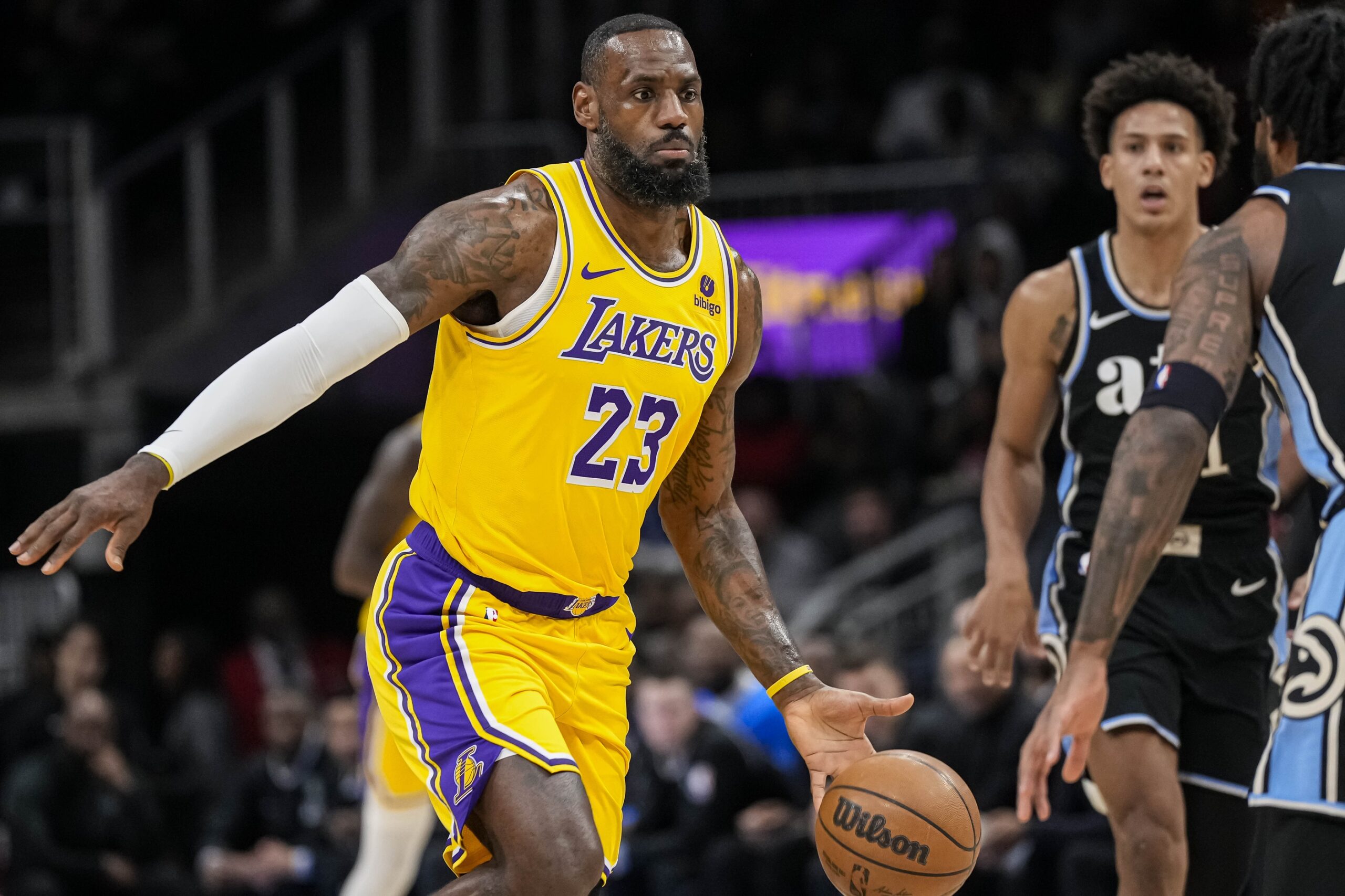 LeBron James of the Los Angeles Lakers dribbles by Jalen Johnson and Saddiq Bey of the Atlanta Hawks