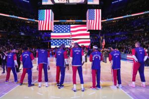 NBA players stand in front of the USA flag at All-Star Game