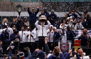 UConn Huskies center Donovan Clingan (32) hold up the championship trophy as the team celebrates in front of a large crowd of fans after the teams victory parade.