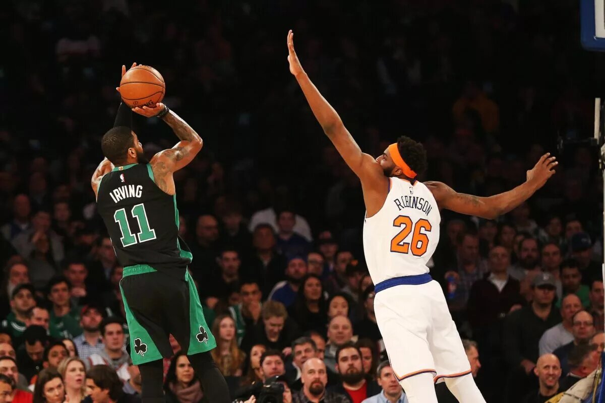 New York Knicks center Mitchell Robinson contests a shot by Kyrie Irving (formerly with Boston Celtics)