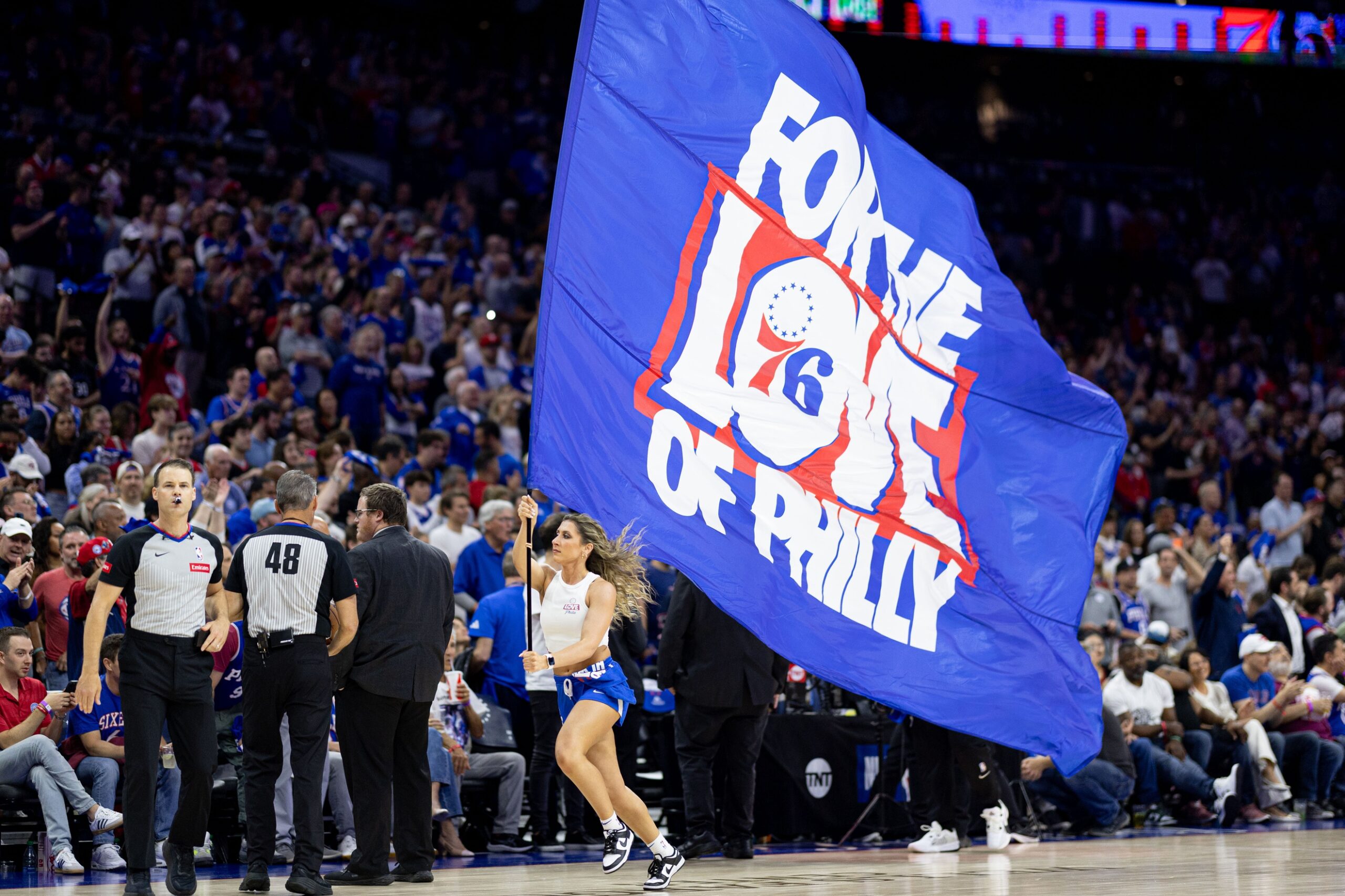 May 2, 2024; Philadelphia, Pennsylvania, USA; Philadelphia 76ers entertainer runs with a large flag during the first half of game six of the first round for the 2024 NBA playoffs against the New York Knicks at Wells Fargo Center. Mandatory Credit: Bill Streicher-USA TODAY Sports Tyrese Maxey