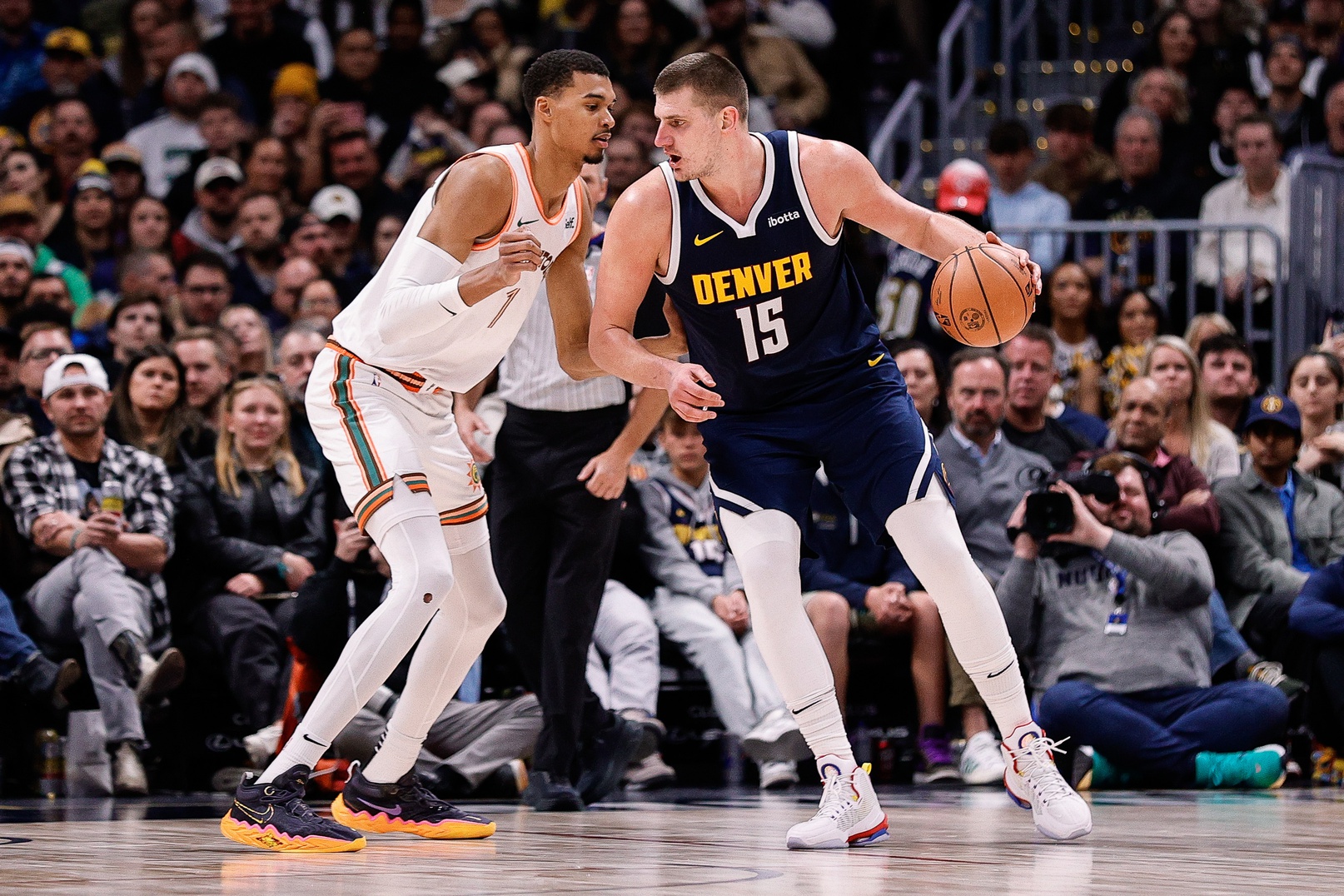 Denver Nuggets center Nikola Jokic (15) controls the ball as San Antonio Spurs center Victor Wembanyama (1) guards in the third quarter at Ball Arena.