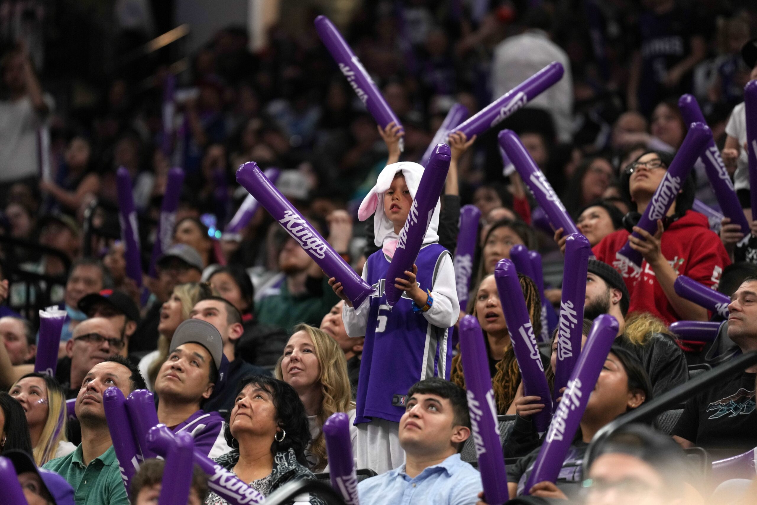 A Sacramento Kings fan wears a bunny hood while banging thunder sticks