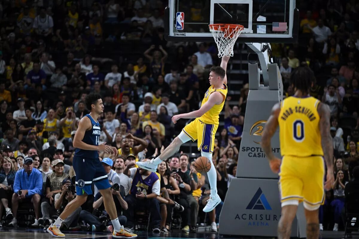 Oct 4, 2024; Palm Desert, California, USA; Los Angeles Lakers guard Dalton Knecht (4) hangs on the rim after dunking against Minnesota Timberwolves center Jesse Edwards (14) during the second half at Acrisure Arena. Mandatory Credit: Jonathan Hui-Imagn Images
