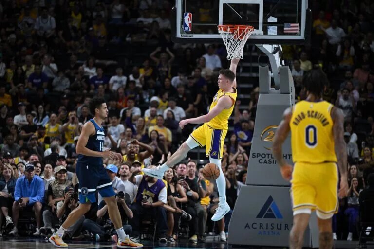 Oct 4, 2024; Palm Desert, California, USA; Los Angeles Lakers guard Dalton Knecht (4) hangs on the rim after dunking against Minnesota Timberwolves center Jesse Edwards (14) during the second half at Acrisure Arena. Mandatory Credit: Jonathan Hui-Imagn Images