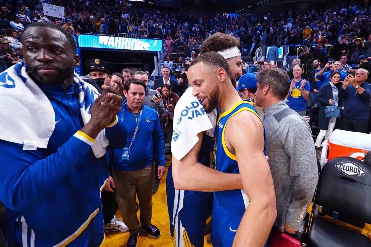 Golden State Warriors guard Stephen Curry (30) hugs guard Klay Thompson (11) beside Golden State Warriors forward Draymond Green (23)