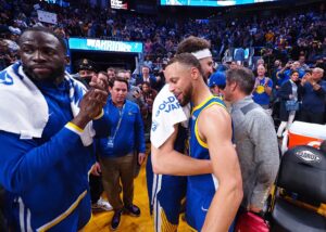 Golden State Warriors guard Stephen Curry (30) hugs guard Klay Thompson (11) beside Golden State Warriors forward Draymond Green (23)