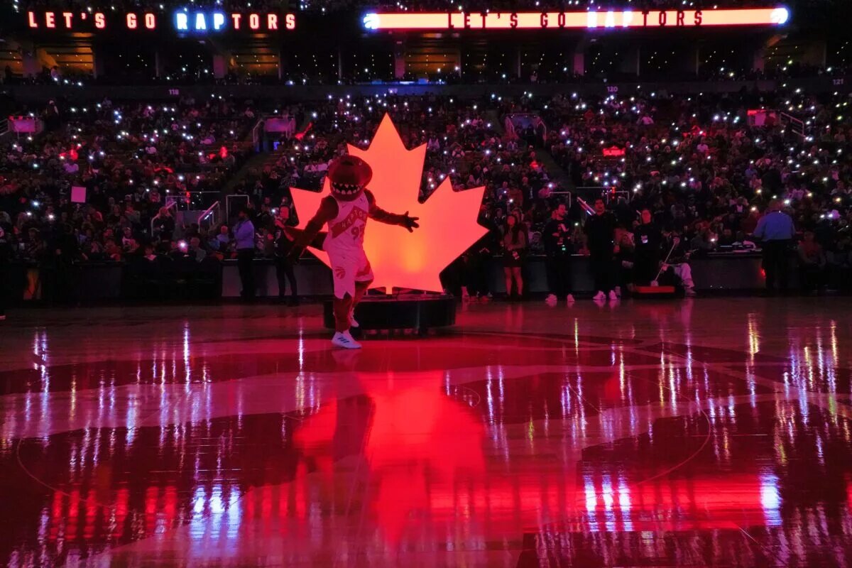 The Toronto Raptors mascot poses in front of a maple logo at center court