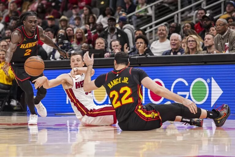 Miami Heat forward Duncan Robinson (55) passes from the floor between Atlanta Hawks guard Keaton Wallace (2) and forward Larry Nance Jr. (22)