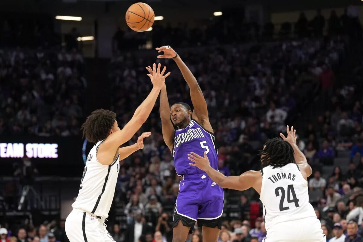 Nov 24, 2024; Sacramento, California, USA; Sacramento Kings guard De'Aaron Fox (5) passes against Brooklyn Nets forward Jalen Wilson (left) and guard Cam Thomas (24) during the fourth quarter at Golden 1 Center.
