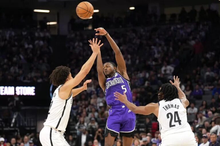 Nov 24, 2024; Sacramento, California, USA; Sacramento Kings guard De'Aaron Fox (5) passes against Brooklyn Nets forward Jalen Wilson (left) and guard Cam Thomas (24) during the fourth quarter at Golden 1 Center.