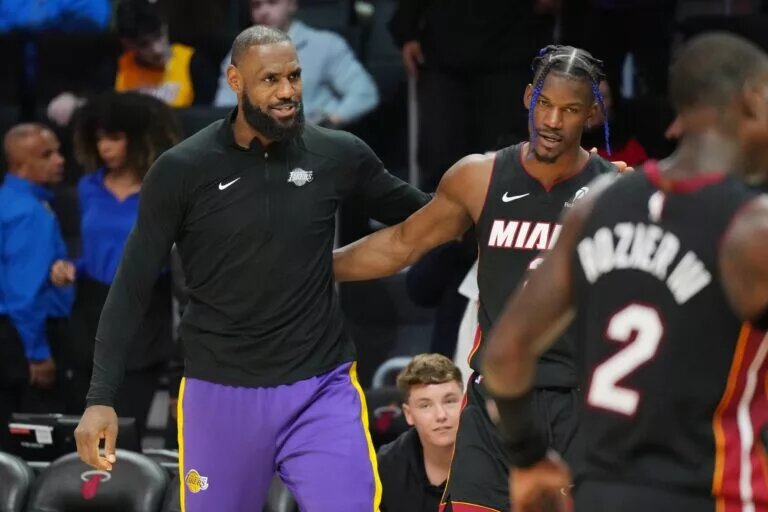 Los Angeles Lakers forward LeBron James and Miami Heat forward Jimmy Butler embrace on the sideline
