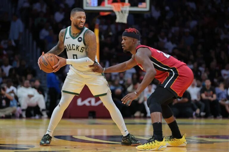 Milwaukee Bucks guard Damian Lillard (0) protects the basketball from Miami Heat forward Jimmy Butler (22)