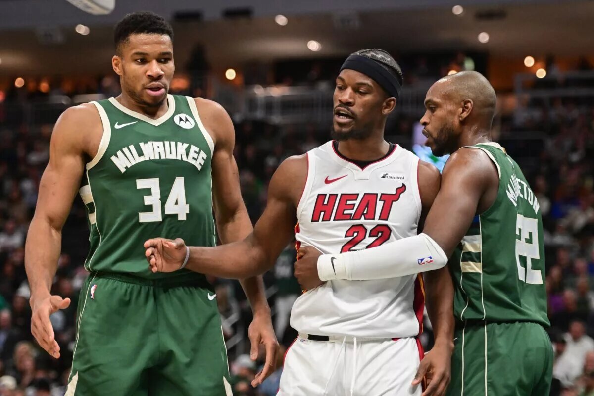Miami Heat forward Jimmy Butler (22) stands between Milwaukee Bucks forwards Giannis Antetokounmpo (34) and Khris Middleton (22)