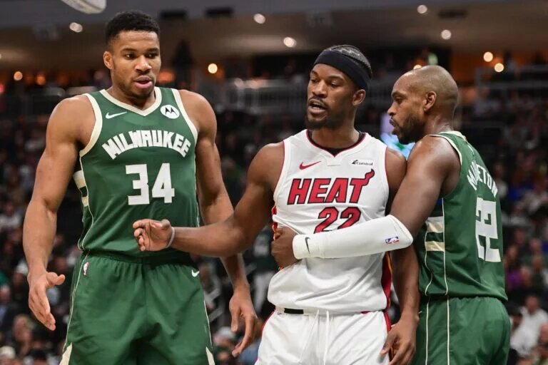 Miami Heat forward Jimmy Butler (22) stands between Milwaukee Bucks forwards Giannis Antetokounmpo (34) and Khris Middleton (22)