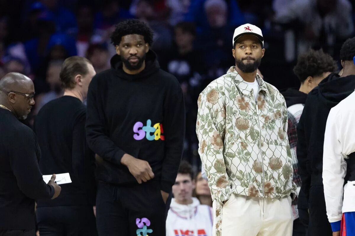 Injured Philadelphia 76ers Paul George (R) and Joel Embiid (L) look on during the first quarter