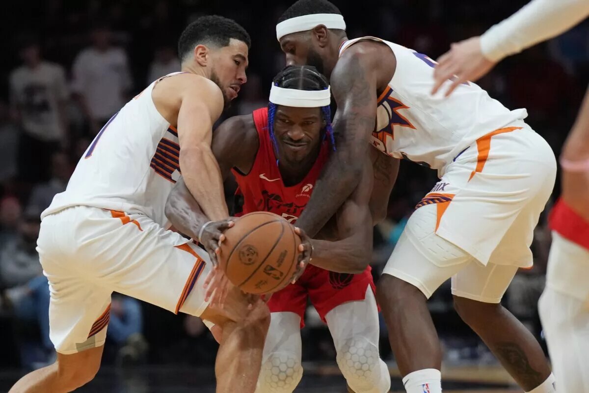 Dec 7, 2024; Miami, Florida, USA; Miami Heat forward Jimmy Butler (22) tries to drive between Phoenix Suns guard Devin Booker (left) and forward Royce O'Neale (right) during the second half at Kaseya Center.