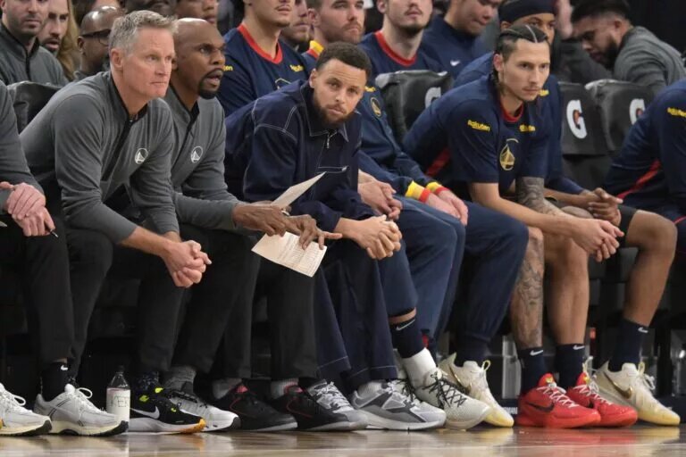 Golden State Warriors guard Stephen Curry (30), center, sits on the bench during the game against the Los Angeles Clippers at Intuit Dome.