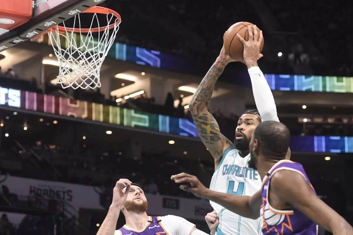 Jan 7, 2025; Charlotte, North Carolina, USA; Charlotte Hornets center Nick Richards (4) looks to pass a rebound during the first half against the Phoenix Suns as Nurkic looks on at the Spectrum center.