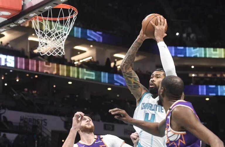 Jan 7, 2025; Charlotte, North Carolina, USA; Charlotte Hornets center Nick Richards (4) looks to pass a rebound during the first half against the Phoenix Suns as Nurkic looks on at the Spectrum center.