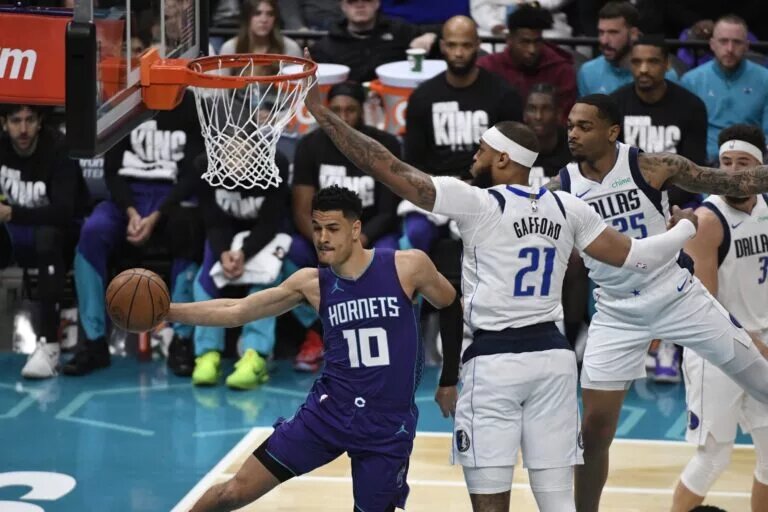 Jan 20, 2025; Charlotte, North Carolina, USA; Charlotte Hornets guard Josh Green (10) passes as he is guarded by Mavs center Daniel Gafford (21) during the first half at the Spectrum Center.