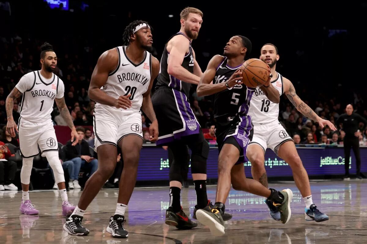 Jan 27, 2025; Brooklyn, New York, USA; Sacramento Kings guard De'Aaron Fox (5) drives to the basket past Brooklyn Nets center Day'Ron Sharpe (20) and guards Tyrese Martin (13) and D'Angelo Russell (1) and Kings forward Domantas Sabonis (11) during the third quarter at Barclays Center. Mandatory Credit: Brad Penner-Imagn Images