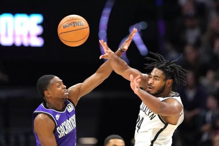 Brooklyn Nets guard Cam Thomas makes a pass while defended by Sacramento Kings guard De'Aaron Fox