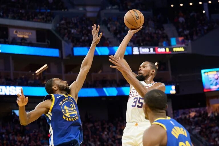Phoenix Suns forward Kevin Durant shoots over Golden State Warriors wings Andrew Wiggins and Jonathan Kuminga