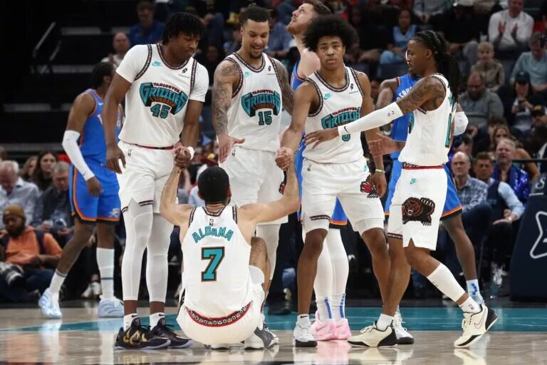 Memphis Grizzlies big man Santi Aldama being helped up by teammates