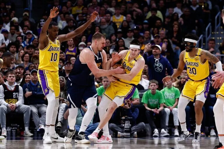 Mar 14, 2025; Denver, Colorado, USA; Los Angeles Lakers guard Austin Reaves (15) steals the ball away from Denver Nuggets center Nikola Jokic (15) as center Christian Koloko (10) and guard Jordan Goodwin (30) defend in the fourth quarter at Ball Arena. Mandatory Credit: Isaiah J. Downing-Imagn Images