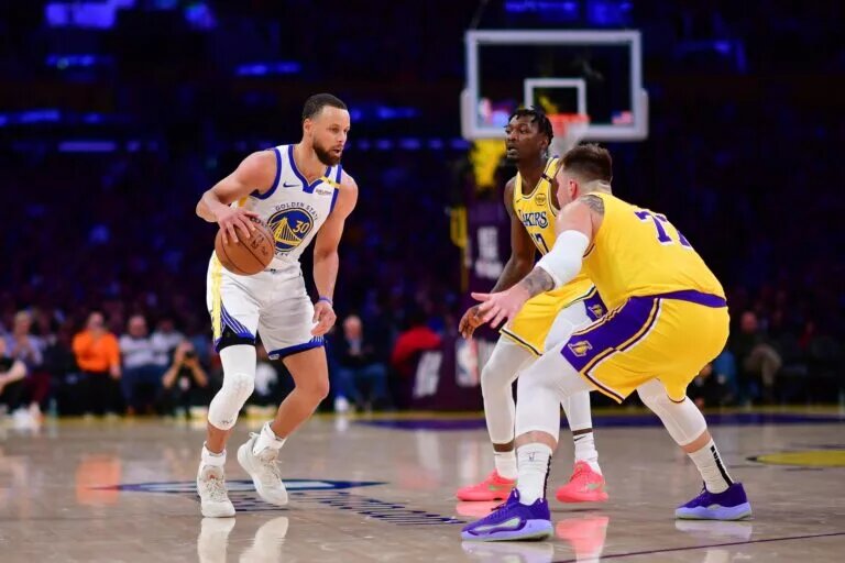 Apr 3, 2025; Los Angeles, California, USA; Golden State Warriors guard Stephen Curry (30) controls the ball against Los Angeles Lakers forward Dorian Finney-Smith (17) and guard Luka Doncic (77) during the second half at Crypto.com Arena. Mandatory Credit: Gary A. Vasquez-Imagn Images