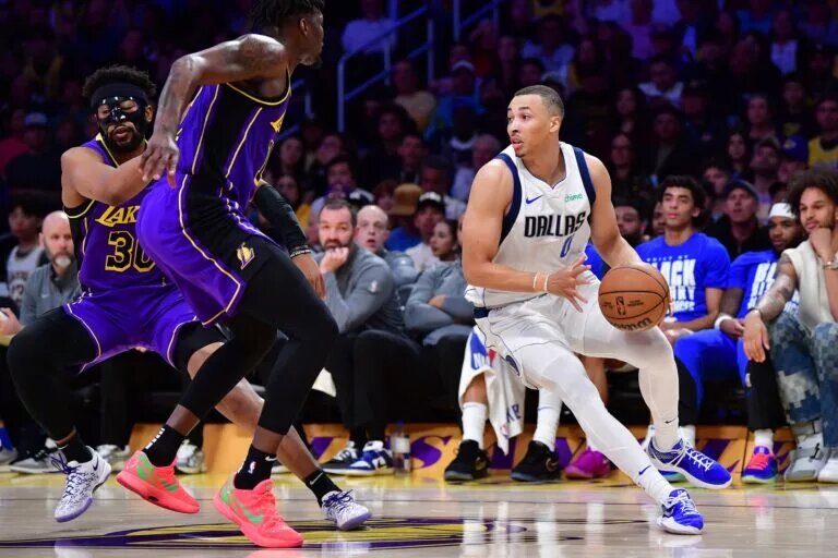 Feb 25, 2025; Los Angeles, California, USA; Dallas Mavericks guard Dante Exum (0) dribbles the ball against Los Angeles Lakers forward Dorian Finney-Smith (17) during the first half at Crypto.com Arena. Mandatory Credit: Gary A. Vasquez-Imagn Images