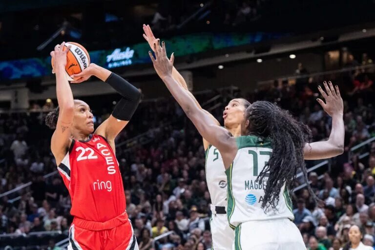May 25, 2025; Seattle, Washington, USA; Las Vegas Aces center A'ja Wilson (22) shoots the ball against Seattle Storm forward Gabby Williams (5) and forward Ezi Magbegor (13) during the first half at Climate Pledge Arena. Mandatory Credit: Stephen Brashear-Imagn Images