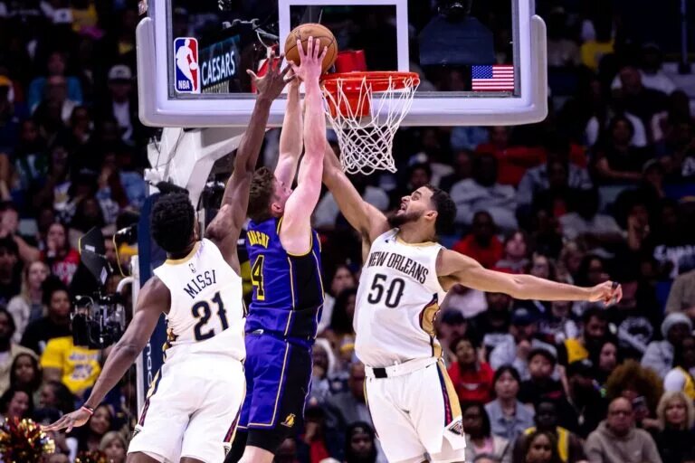 Nov 16, 2024; New Orleans, Louisiana, USA; Los Angeles Lakers guard Dalton Knecht (4) dunks over New Orleans Pelicans forward Jeremiah Robinson-Earl (50) and center Yves Missi (21) during the second half at Smoothie King Center. Mandatory Credit: Stephen Lew-Imagn Images
