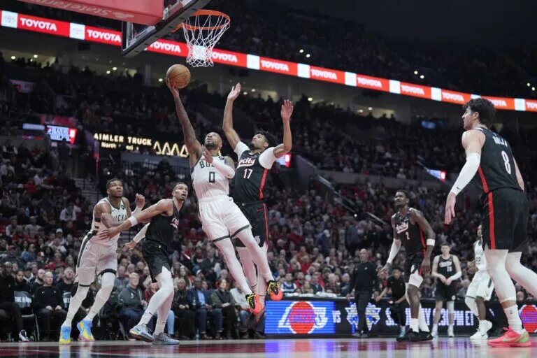 Jan 28, 2025; Portland, Oregon, USA; Milwaukee Bucks point guard Damian Lillard (0) shoots the ball past Portland Trail Blazers shooting guard Shaedon Sharpe (17) during the second half at Moda Center. Mandatory Credit: Soobum Im-Imagn Images